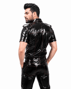 Side profile of a male model wearing a black PVC fetish shirt with shiny finish, detailed collar, and shoulder epaulets, against a white background.