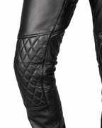 Black leather pants with quilted detailing on thighs and knees, showing a high waist with a belt and zipper fly, styled for biker gear.